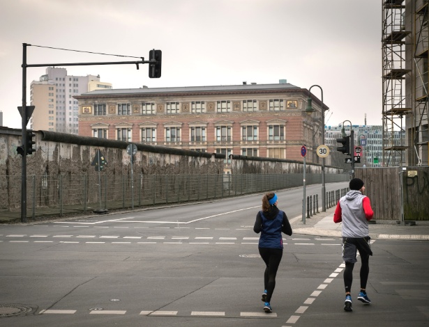 Atletas correm em frente a um trecho do muro de Berlim, na Alemanha - Gordon Welters/The New York Times