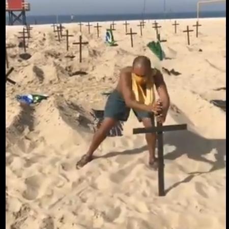 O taxista Marcio Antônio do Nascimento Silva recoloca cruzes na areia de Copacabana depois que um homem as retirou - Reprodução/Twitter