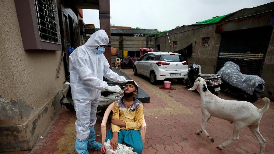 24.jul.2020 - Profissional da saúde usando roupa protetora faz teste em garoto em meio à pandemia do novo coronavírus em Ahmedabad, na Índia - Amit Dave/Reuters
