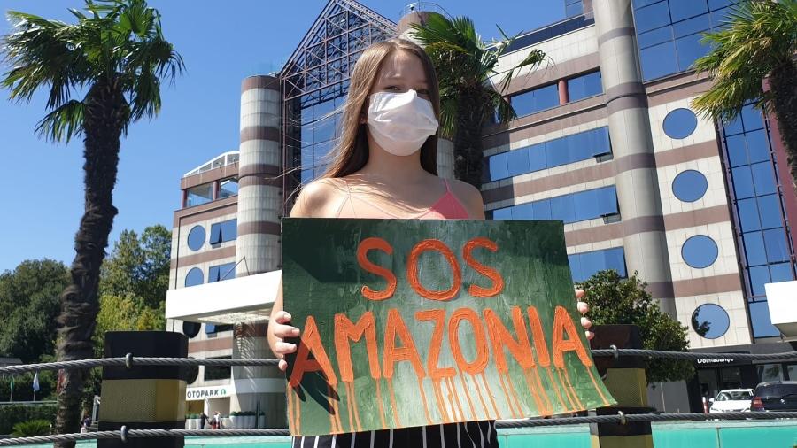 Ativista Deniz Çevikus segura cartaz com SOS Amazônia - Reprodução/Twitter
