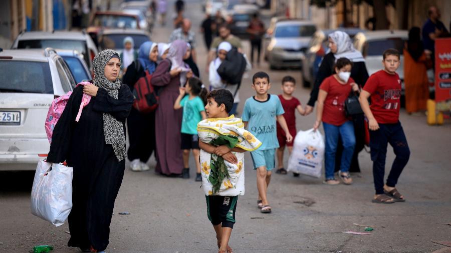 13.out.23 - Palestinos carregando seus pertences fogem para áreas mais seguras na Cidade de Gaza após ataques aéreos israelenses