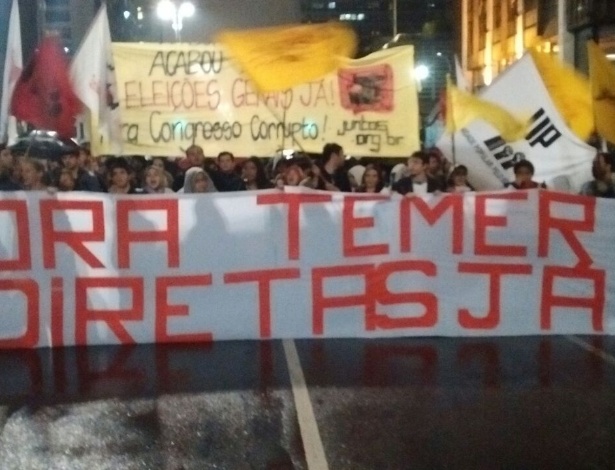 18.mai.2017 - Com bandeiras e sob chuva, manifestantes protestam em São Paulo com faixa de "Fora Temer, Diretas Já!" - UOL