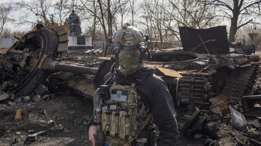 28.mar.2022 - Um militar ucraniano passa pelos destroços de um tanque russo na vila de Lukyanivka, nos arredores da capital Kiev, na Ucrânia. - MARKO DJURICA/REUTERS