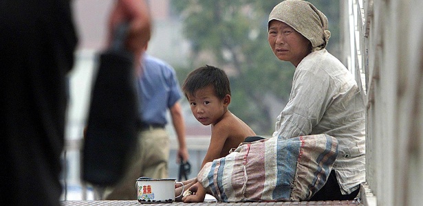 Mulher pede esmola com seu filho em Pequim, na China - Frederic J. Brown/AFP