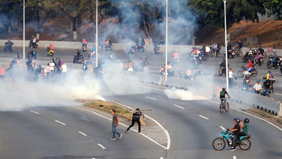 30.abr.2019 - Pessoas reagem ao uso de gás lacrimogêneo em protesto perto da base "La Carlota", em Caracas, na Venezuela - Carlos Garcia Rawlins/Reuters