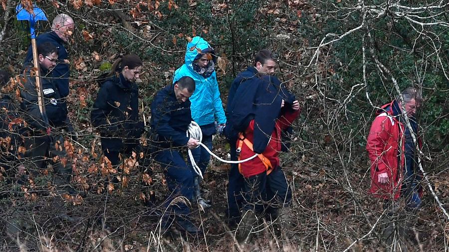 Policiais caminham com Caouissin perto do rio Aulne, no oeste da França, numa reconstituição do crime realizada em 2019 - Fred Tanneau / AFP