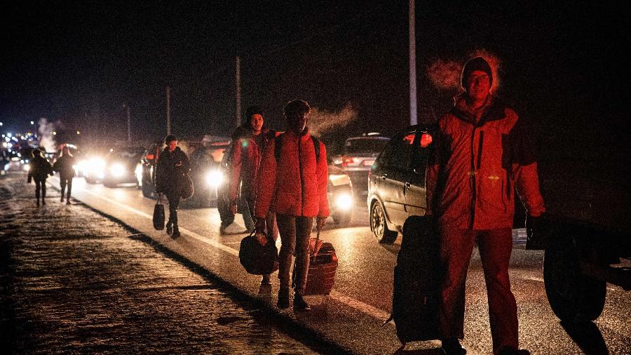 Pessoas em carros e a pé se deslocam para atravessar a fronteira entre Ucrânia e Polônia na madrugada de sábado (26) - Dimitar Dilkoff/AFP