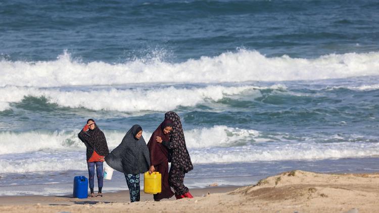 Meninas palestinas enchem galões com água do mar para usar em um acampamento em Rafah