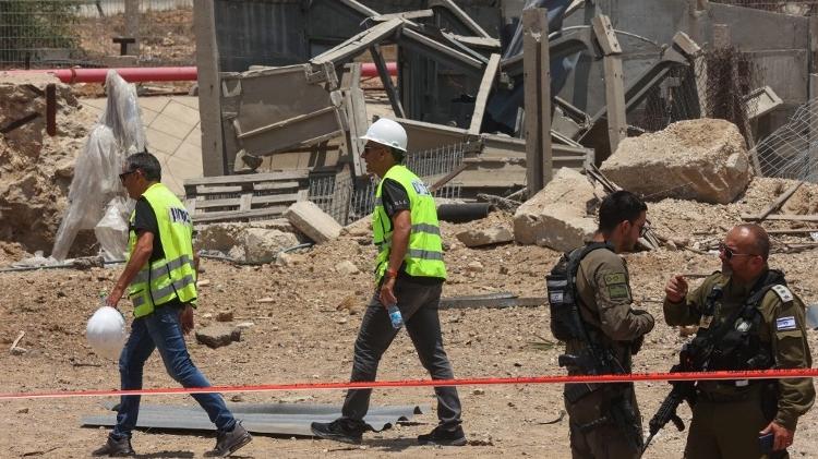 23.jun.2025 - Membros das forças de segurança e serviços de emergência israelenses trabalham em uma área isolada no local do impacto de um foguete iraniano, perto da cidade de Ashdod, no sul do país
