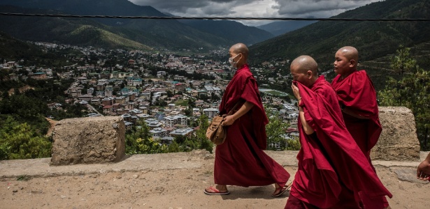 Monges budistas caminham por estrada com Thimphu, no Butão, ao fundo - Gilles Sabrie/ The New York Times