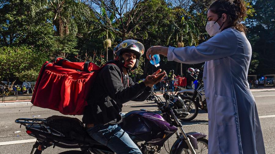 Entregador recebe álcool em gel distribuído na região da avenida Paulista, em São Paulo - Anderson Lira/ Framephoto/ Estadão Conteúdo