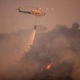 A helicopter flies over a fire in the Sierra de Mijas region of the Spanish province of Malaga, 15 July 2022 - JORGE GUERRERO / AFP