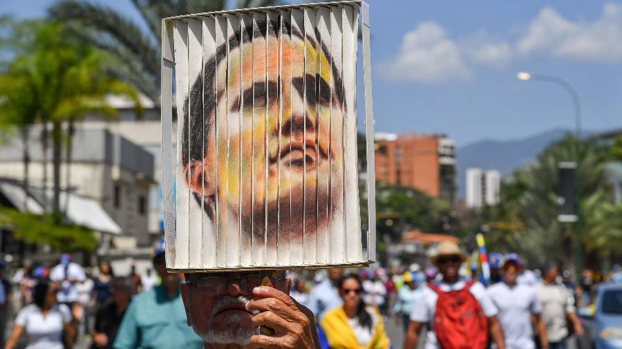 4.mar.2019 - Opositor de Maduro segura um retrato de Juan Guaidó, o autoproclamado presidente internino da Venezuela, enquanto aguarda seu retorno em Caracas - Yuri Cortez/AFP