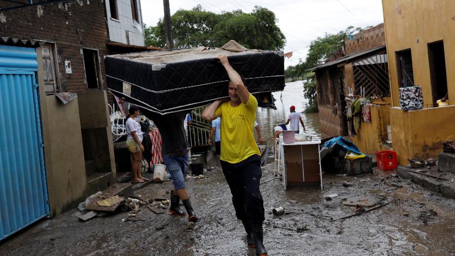 Homem carrega cama em cima dos ombros após estragos das chuvas em Itabuna, na Bahia - Amanda Perobelli/Reuters