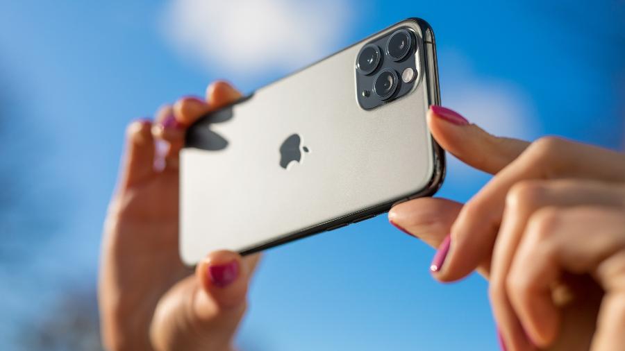 Pessoa tirando foto com câmera traseira do iPhone 11 Pro, que tem três sensores - Getty Images
