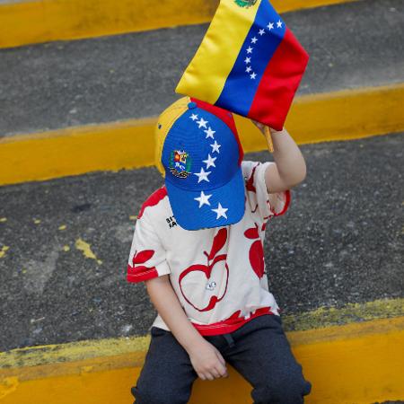 Menino segura bandeira da Venezuela durante eleição neste domingo (28), em Caracas