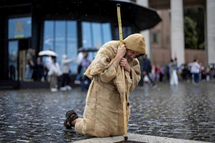 Homem se ajoelha na praça de São Pedro antes do conclave que escolherá o novo papa Homem se ajoelha na praça de São Pedro antes do conclave que escolherá o novo papa