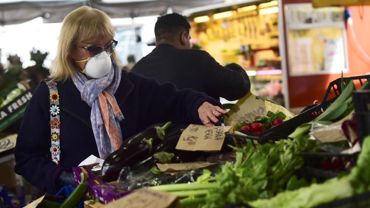 Em Turim, mulher usando máscara verifica vegetais em mercado - Massimo Pinca/Reuters
