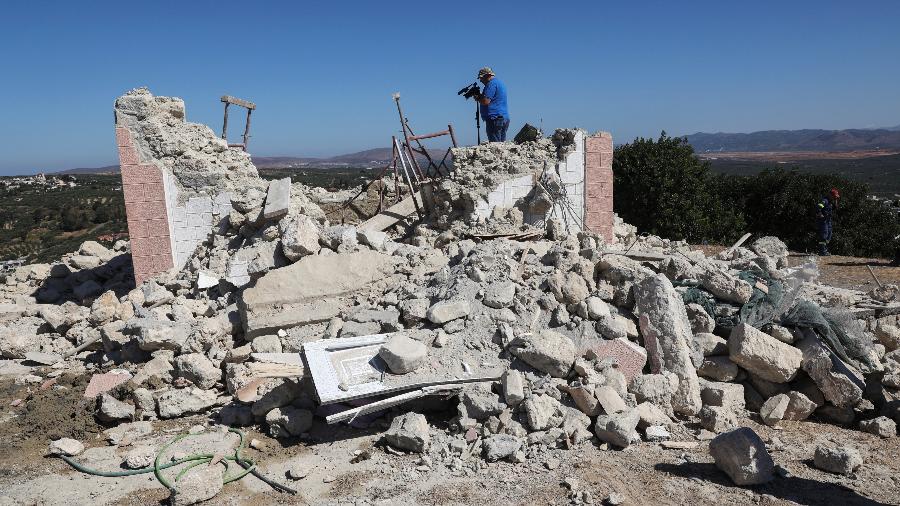 Um operador de câmera filma em meio aos escombros de uma igreja demolida após um terremoto na cidade de Arkalochori, na ilha de Creta, na Grécia - Stefanos Rapanis/REUTERS