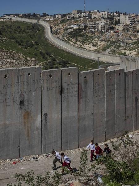Crianças palestinas caminham perto de muro que separa Jerusalém de Abu Dis, na Cisjordânia - Lalo de Almeida/Folhapress