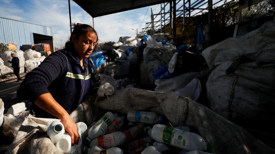 Paola Godoy, que trabalha como catadora de resíduos, coloca garrafas vazias de leite em sacola para serem recicladas em Lomas de Zamora, nos subúrbios de Buenos Aires - Agustin Marcarian/Reuters