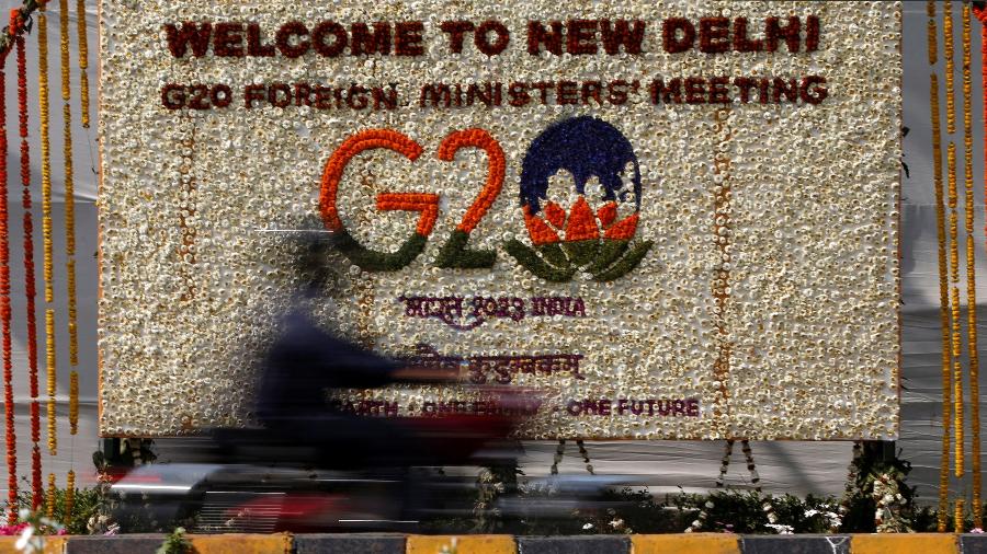 Um motorista passa por um painel decorado com flores para dar as boas-vindas aos ministros das Relações Exteriores do G20 em Nova Delhi, Índia - Amiit Dave/Reuters