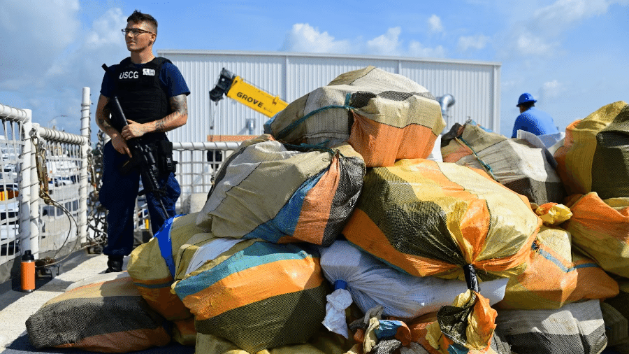 Membro da Guarda Costeira Americana ao lado de vários sacos apreendidos com cocaína - Divulgação/United States Coast Guard News