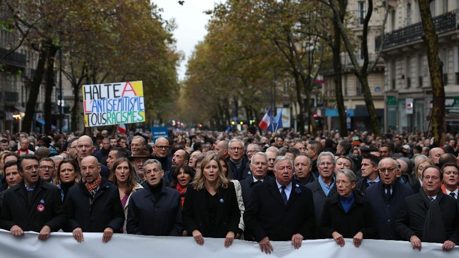 Autoridades cantam o hino nacional francês atrás de uma faixa que diz "Pela República, Contra o antissemitismo" durante uma marcha em Paris