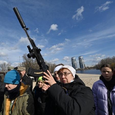 25.fev.2022 - Mulher empunha arma durante treinamento aberto, organizado para civis por veteranos de guerra e voluntários, que ensinam o manuseio básico de armas e primeiros socorros em Kiev - Genya Savilov/AFP