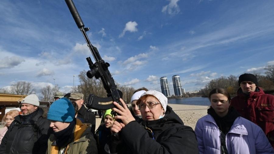 25.fev.2022 - Mulher empunha arma durante treinamento aberto, organizado para civis por veteranos de guerra e voluntários, que ensinam o manuseio básico de armas e primeiros socorros em Kiev - Genya Savilov/AFP