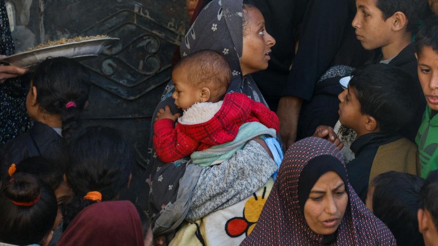 Mulheres e crianças aguardam para receber comida em Rafah, na Faixa de Gaza, em meio a guerra entre Israel e o Hamas
