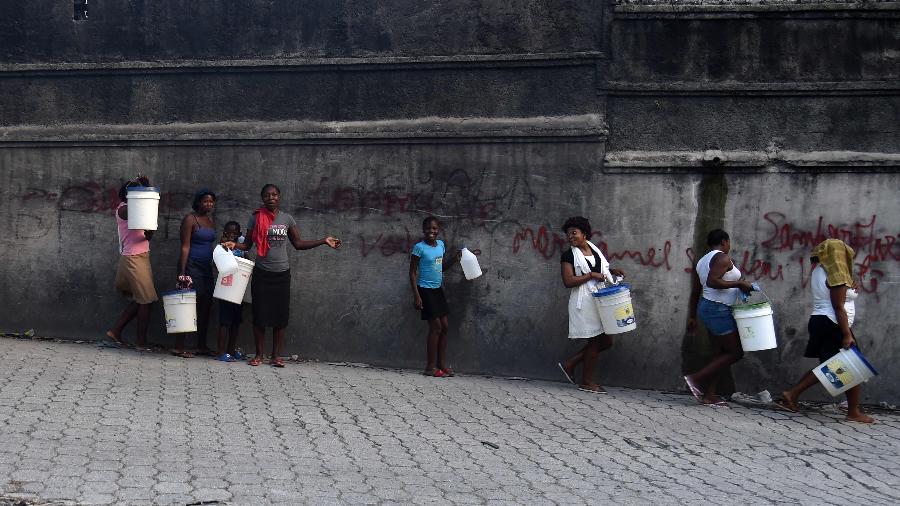 14.fev.2019 - Um grupo de mulheres e crianças caminham para comprar água para uma área próxima na comuna de Petion Ville, na capital haitiana Porto Príncipe - HECTOR RETAMAL / AFP