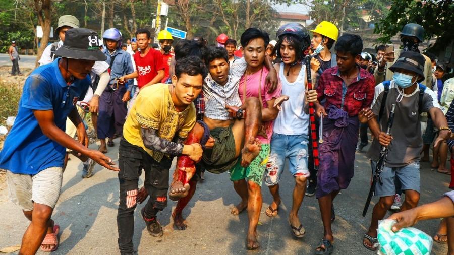 Homem ferido é levado até um local seguro durante manifestação contra os militares em Yangon - março de 2021 - Getty Images