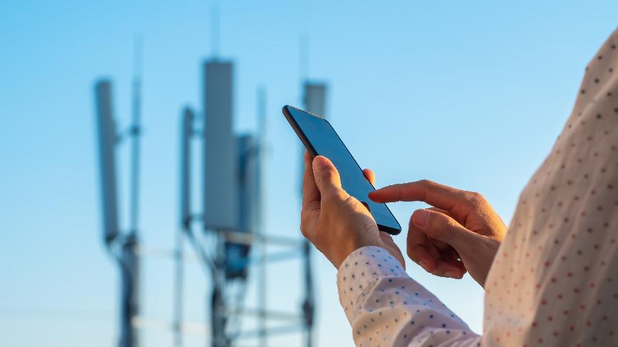 Torre de comunicação do 5G e uma pessoa usando celular
