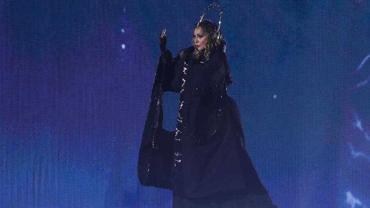 Madonna surge em vestido longo e azul escuro, com um aplique de cabeça