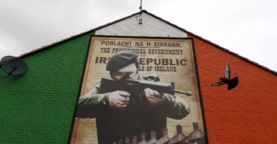 9.set.2015 - Pombo voa próximo a um mural com imagem em apoio ao Exército Republicano Irlandês (IRA), no norte de Belfast, na Irlanda do Norte