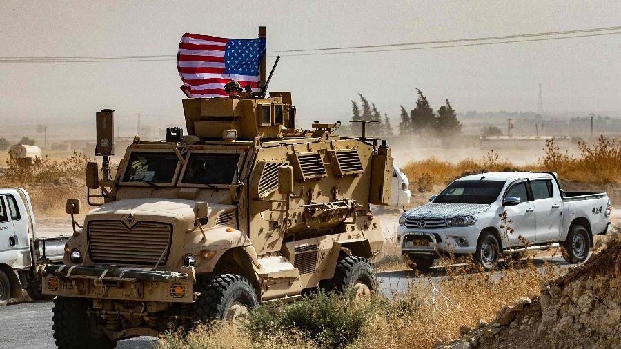 Um soldado dos EUA está sentado no topo de um veículo blindado durante uma manifestação de curdos sírios contra ameaças turcas - Delil Souleiman/AFP