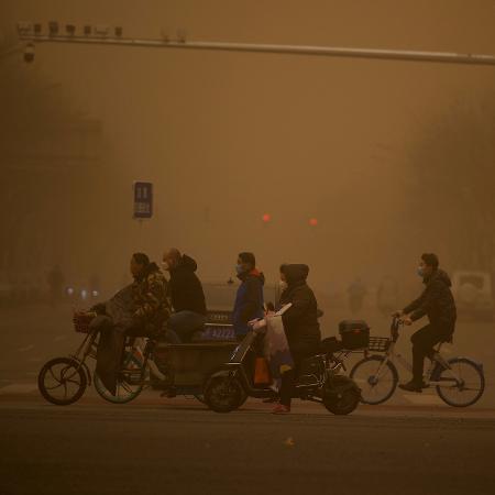 15.mar.2021 - Pessoas atravessam a rua durante tempestade de areia em Pequim - Noel Celis/AFP