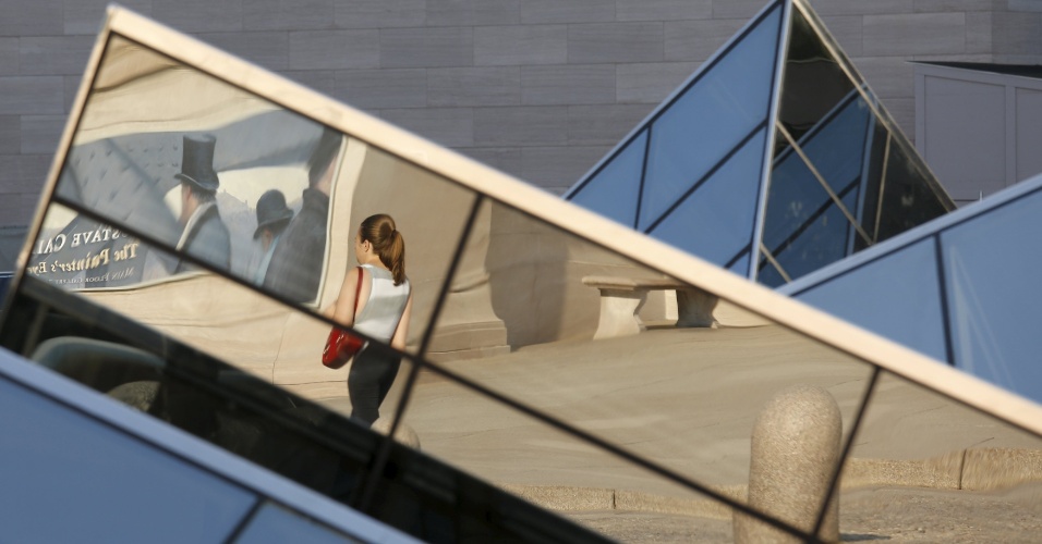 1º.set.2015 - Reflexo nas pirâmides de vidro da National Gallery of Art mostra uma mulher andando na exposição "Gustave Caillebotte: olho do pintor", em Washington (EUA)