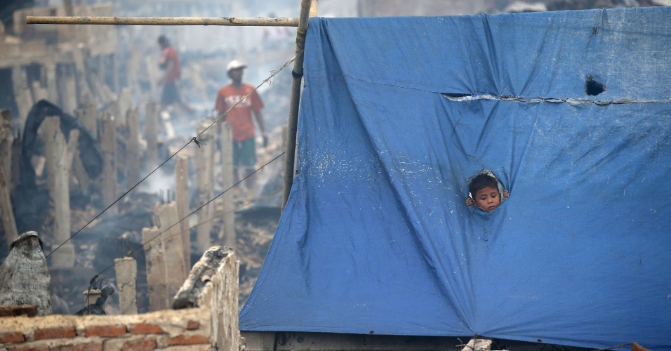 9.set.2015 - Menino mora em abrigo improvisado criado após um incêndio destruir centenas de casas na área em Jacarta, na Indonésia