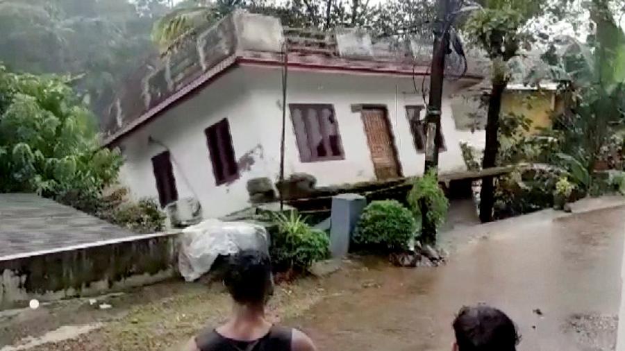 Pessoas observam casa sendo arrastada pela correnteza do rio em Kottayam, na Índia - Reuters