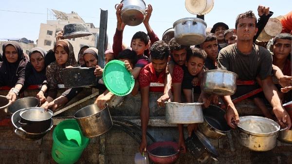 Palestinos recebem sopa de lentilha em um ponto de distribuição de alimentos na Cidade de Gaza, em 2 de agosto de 2025 
