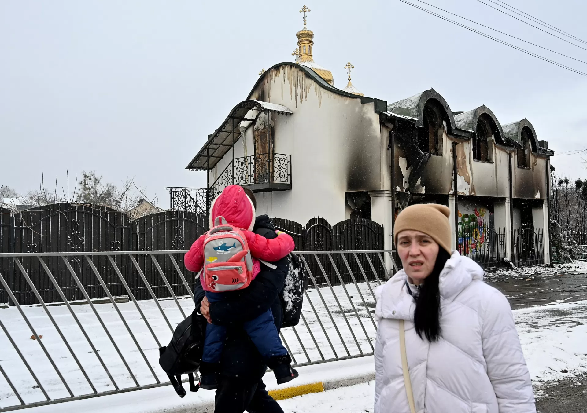 8 mar. 2022 - Mulher passa por prédio danificado ao deixar com a família a cidade de Irpin, ao noroeste de Kiev, na Ucrânia - Sergei Supinsky/AFP