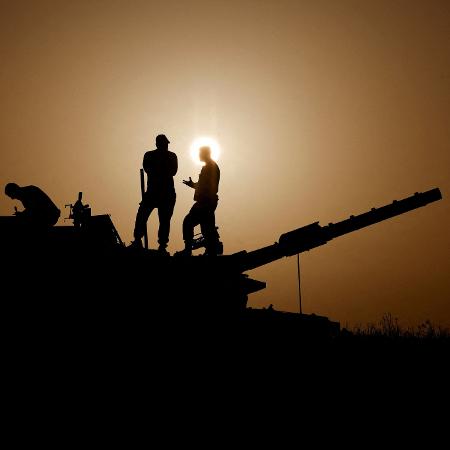 23.nov.2023 - Ao sul de Israel, próximo à fronteira com Gaza, soldados conversam em cima de um tanque de guerra