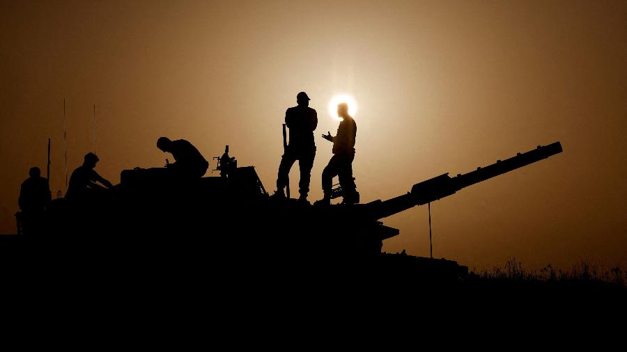 23.nov.2023 - Ao sul de Israel, próximo à fronteira com Gaza, soldados conversam em cima de um tanque de guerra - Amir Cohen/Reuters