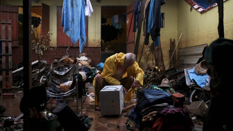 Morador de Eldorado do Sul limpa eletrodoméstico em sua casa atingida pelas enchentes no Rio Grande do Sul
