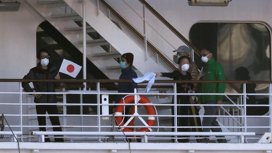 Passageiros do navio Diamond Princess acenam com bandeira japonesa durante quarentena por coronavírus - KIM KYUNG-HOON