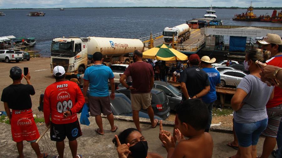 Pessoas aplaudem e observam a chegada de caminhões com parte do carregamento de 160 mil m³ de oxigênio que saíram de Porto Velho (RO) pela BR-319, chegam no Porto da Ceasa, no fim da manhã deste domingo (24) em Manaus (AM) - EDMAR BARROS/ESTADÃO CONTEÚDO
