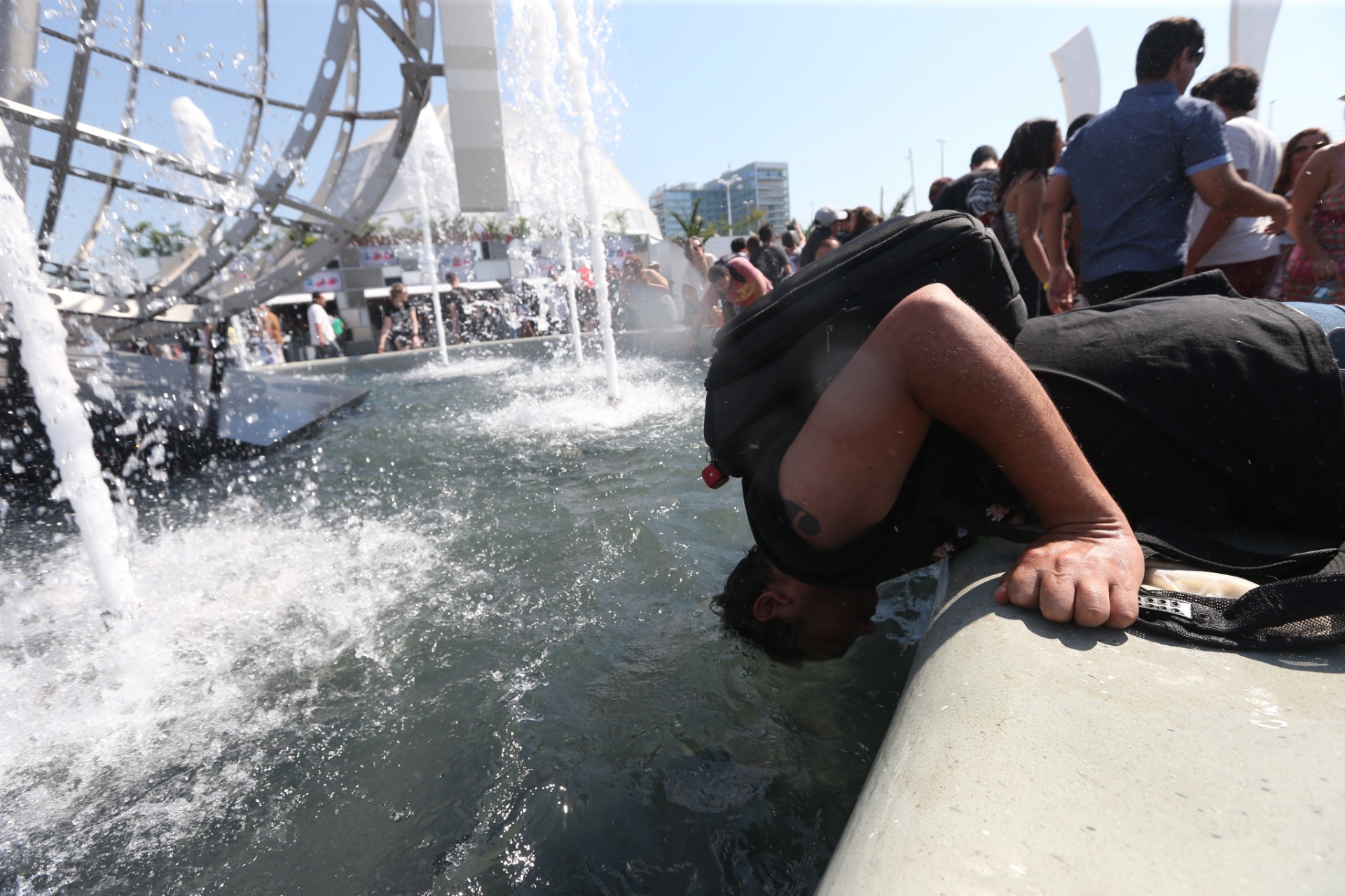 24.set.2015 - Fã não suporta o calor e coloca a cabeça em fonte para se refrescar na Cidade do Rock após a abertura dos portões para o 4º dia do festival Rock in Rio, na Barra da Tijuca, zona oeste do Rio de Janeiro. A previsão é que os termômetros marquem até 38ºC nesta quinta-feira - Fábio Motta/ Estadão Conteúdo