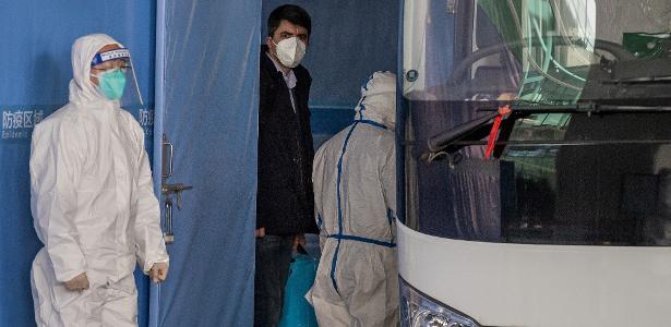 14.jan.2021 - Investigador da OMS (de jaqueta preta) enviado à China para apurar a origem do coronavírus embarca em um ônibus acompanhado de especialistas chineses (com roupas de proteção brancas)